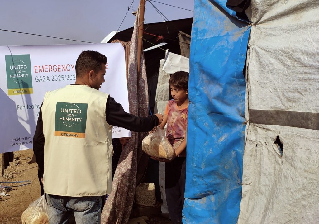 Ein Mann verteilt frisch gebackenes Brot an einen Jungen in Gaza