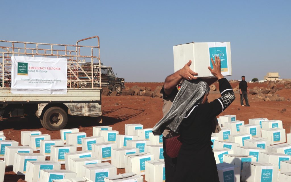 Eine Frau erhält im Rahmen einer Verteilungsaktion im Süden Syrien ein Paket mit diversen Lebensmitteln von United for Humanity